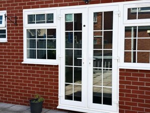 A red brick house with white-framed windows and a sliding glass door. - RS Prime Homestay  (Solihull)