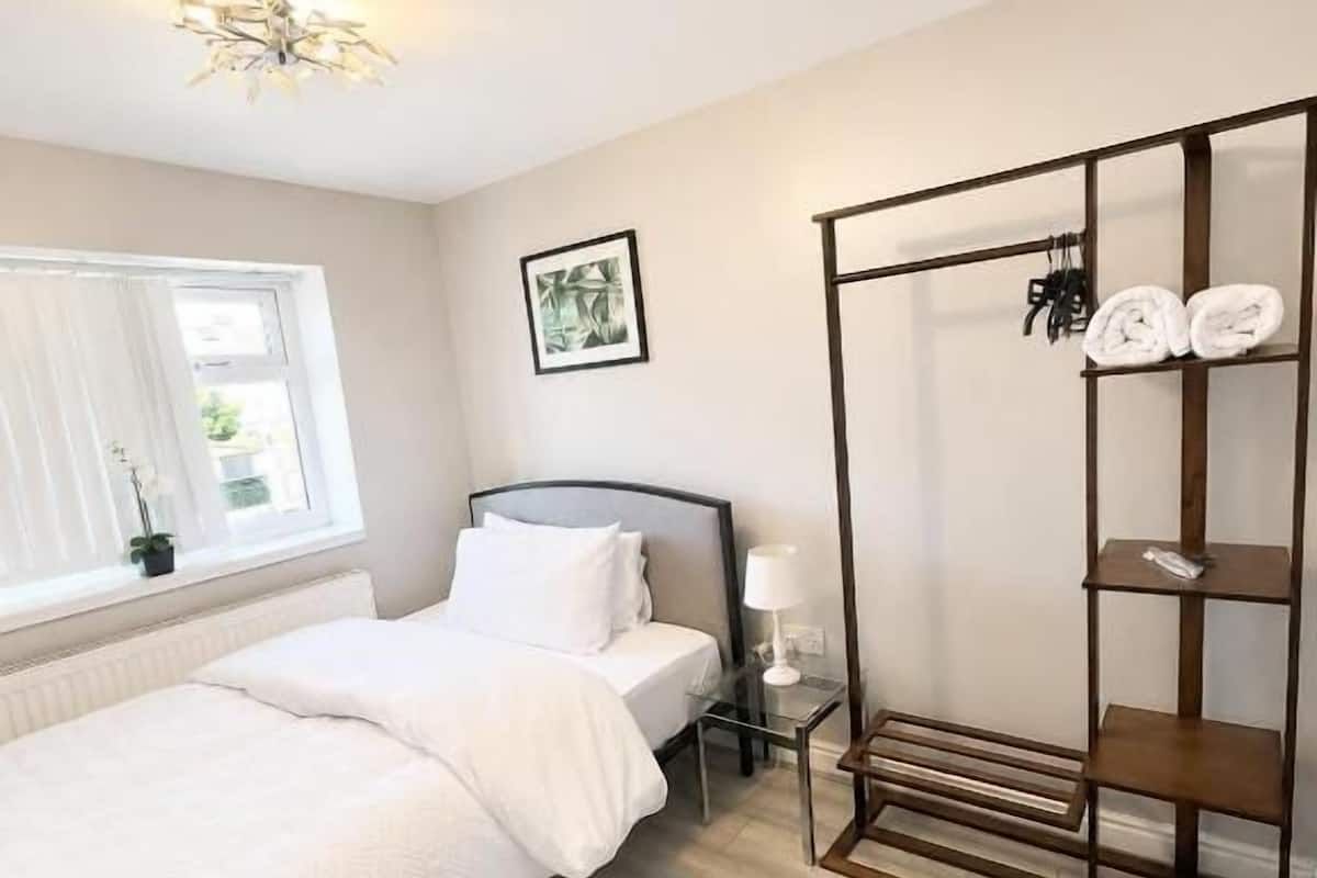 A bedroom with a bed, bedside table, lamp, and a wardrobe.