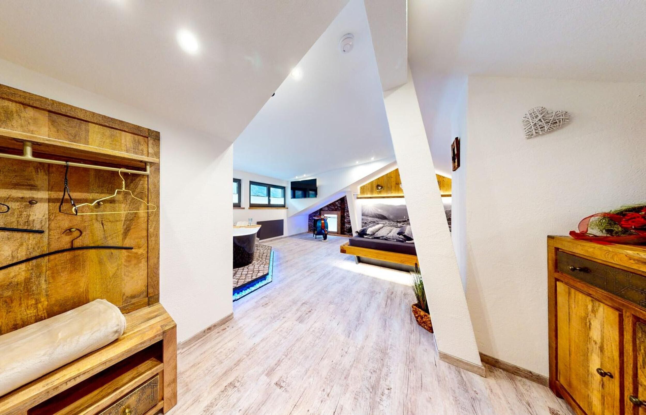 Un vaste espace de vie de style loft, doté d’un plafond haut, d’un plancher en bois, d’une banquette intégrée, d’un coin salon avec des coussins et d’un escalier menant à un niveau supérieur.