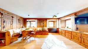 Eine geräumige Küche mit Holzausstattung, ein Essbereich mit rundem Tisch und Stühlen sowie eine integrierte Sitzecke.