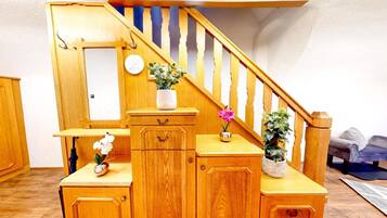 A wooden staircase with a handrail, a small table with a vase of flowers, and a cabinet with drawers.
