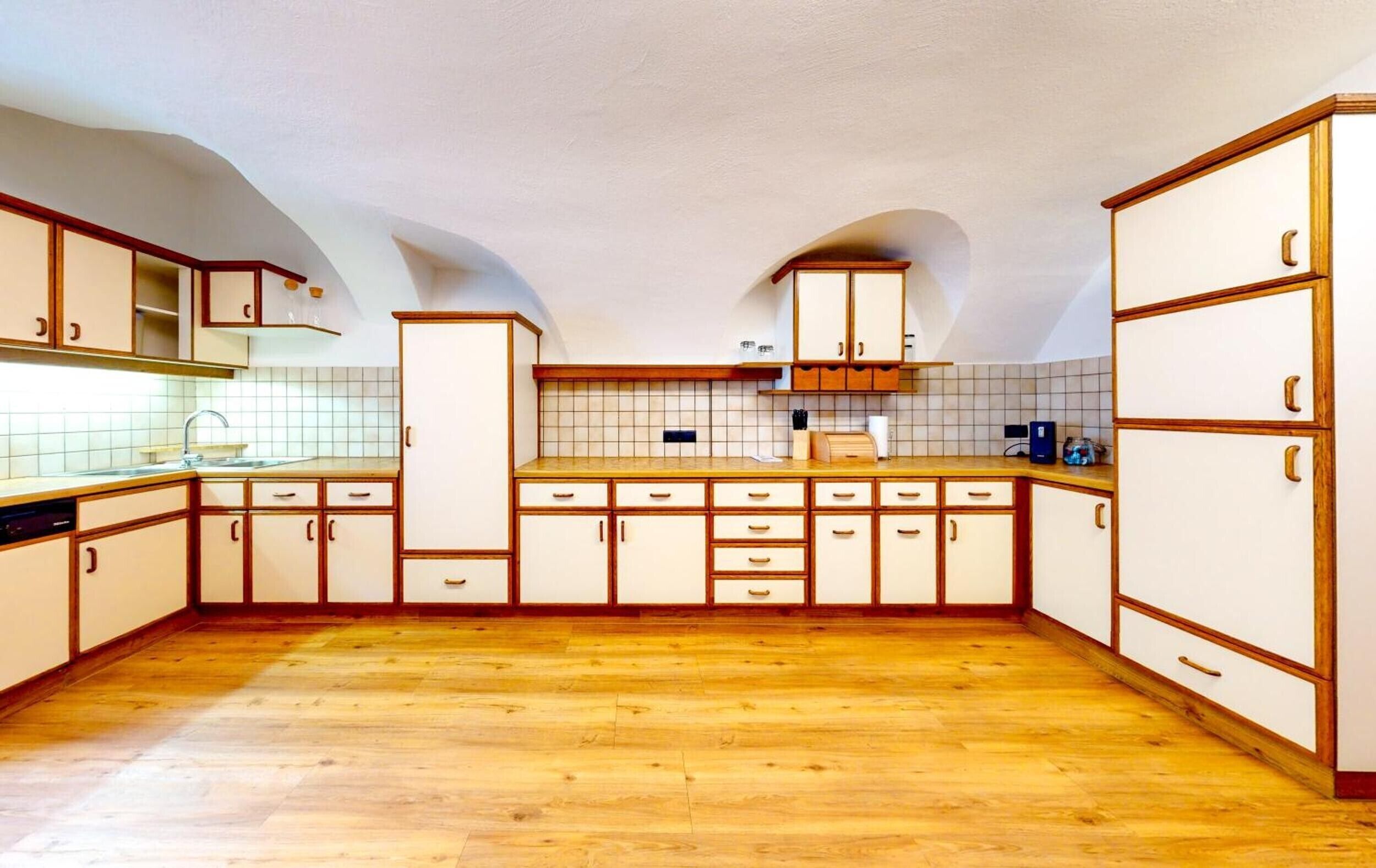 A kitchen with wooden cabinets, a tiled backsplash, and a wooden floor.