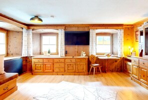Ein Holzblockhaus-Interieur mit einem großen Holzschrank, einem Sessel und einem Fernseher.