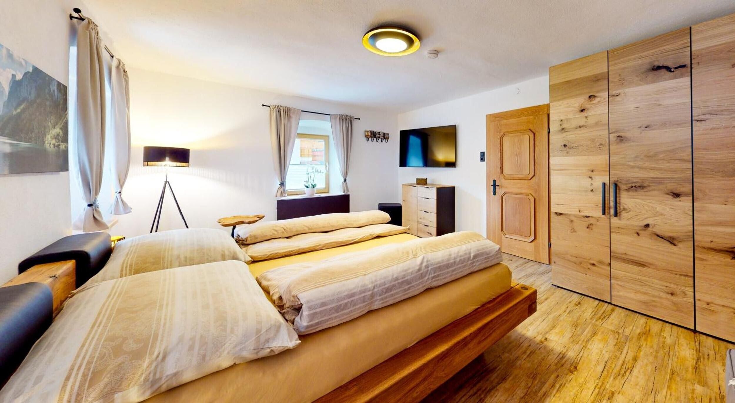 Une chambre à coucher avec un lit, un bureau, une armoire, une télévision et une fenêtre.