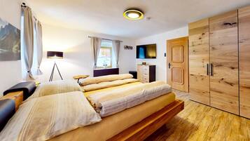 Une chambre à coucher avec un lit, un bureau, une armoire, une télévision et une fenêtre.