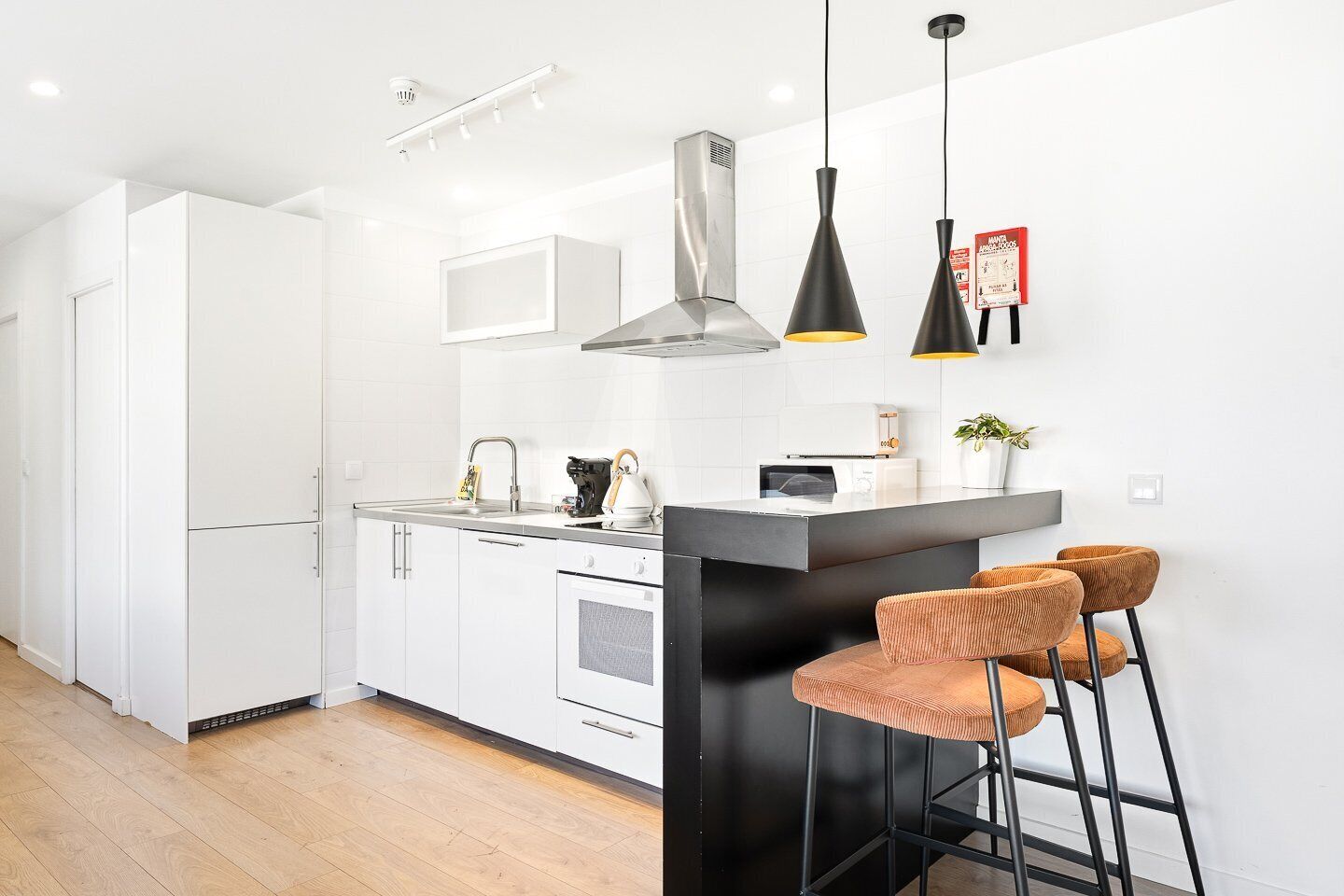 A modern kitchen with white cabinets, a black countertop, and two pendant lights.