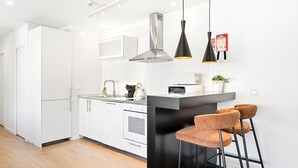 Une cuisine moderne avec des meubles blancs, un plan de travail noir et deux suspensions lumineuses.