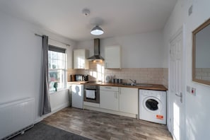 Une cuisine compacte équipée d’un four, d’un micro-ondes et d’un lave-linge intégrés.