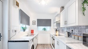Una cocina funcional con lavadora, lavaplatos y estufa.