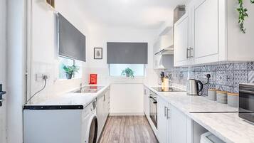A compact kitchen with a washing machine, a sink, and a stove.