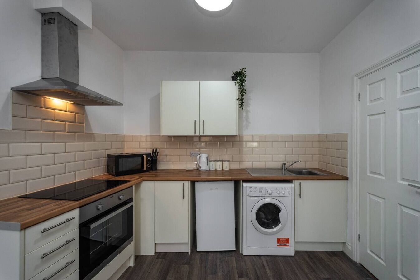 A compact kitchen with a microwave, oven, dishwasher, and a sink.