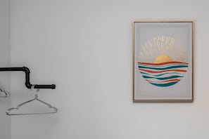 A framed artwork of a stylized sun and waves on a wall.