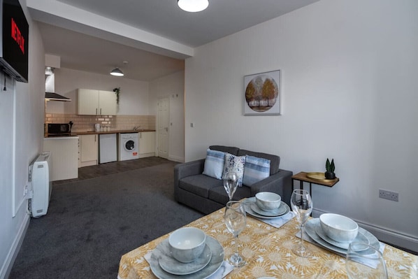 A modern apartment with a dining area, kitchen, and living room.