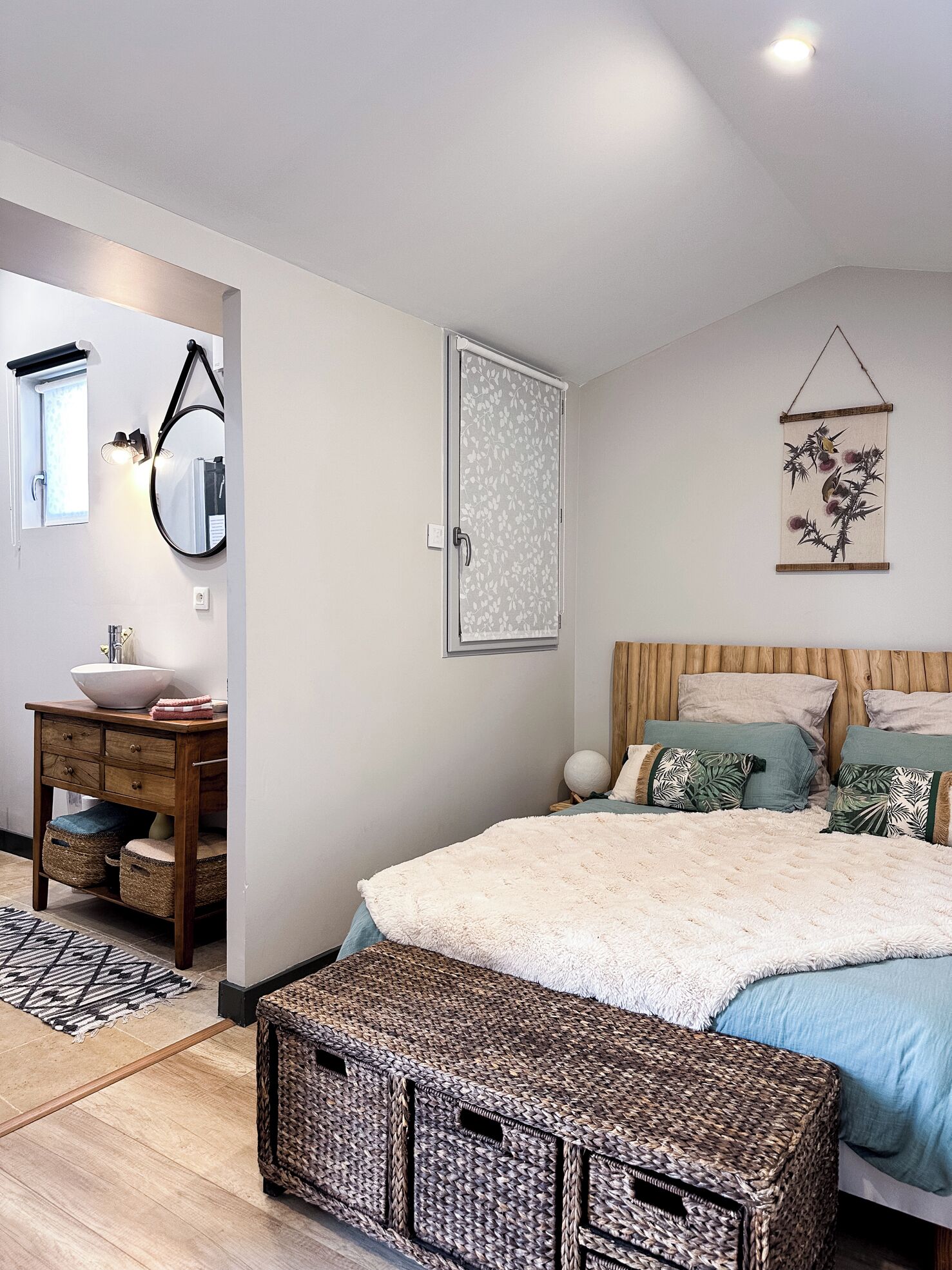 A bedroom with a bed, bedside tables, a mirror, a wall-mounted artwork, and a window.