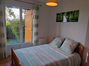 Ein Schlafzimmer mit Bett, einem Fenster mit Vorhängen, einem Heizkörper und einem Bild an der Wand.
