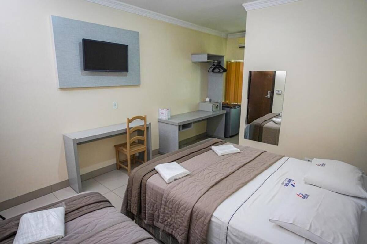 Habitación de hotel con dos camas, un escritorio, una silla, un televisor y un espejo.