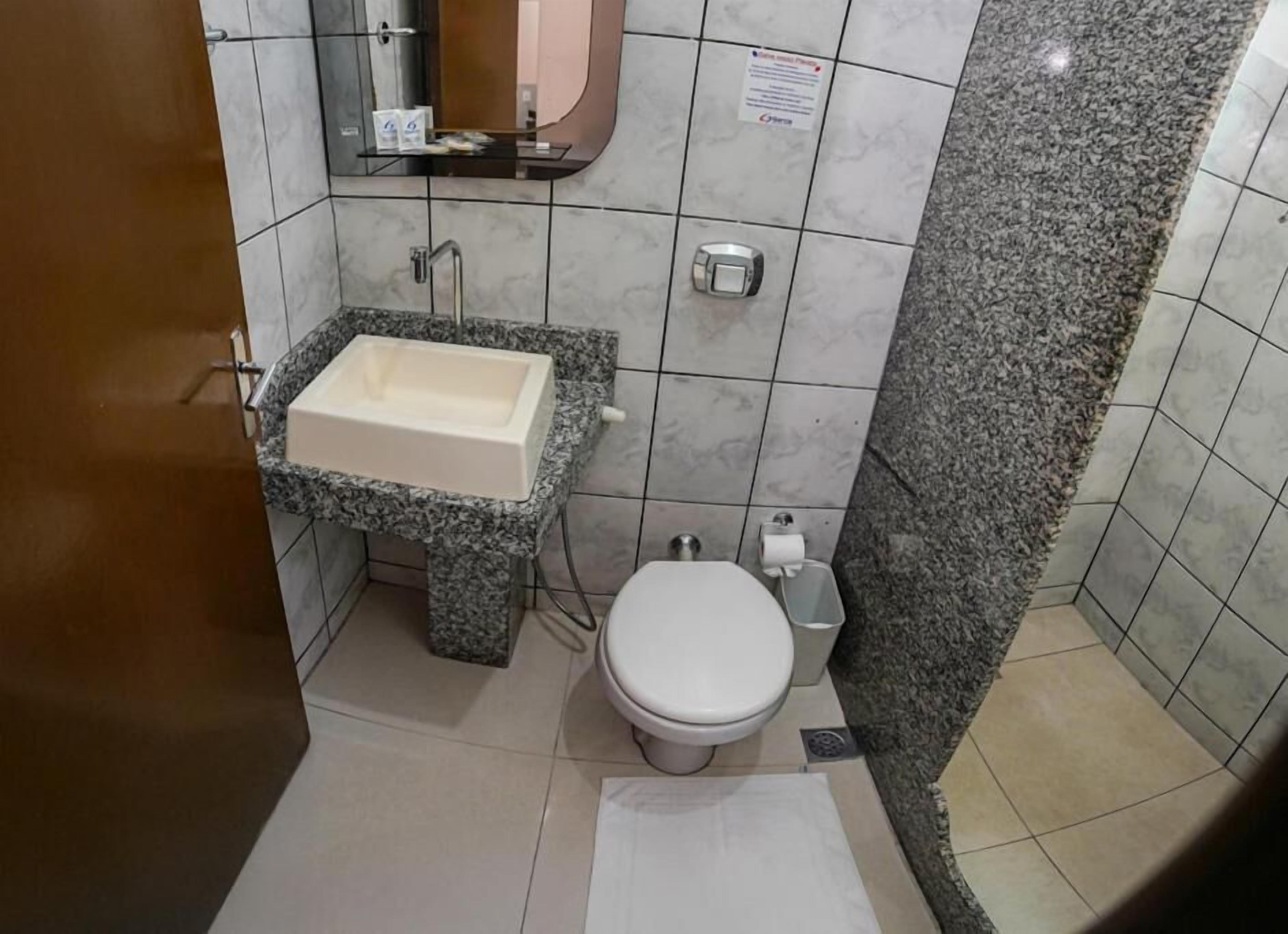 A bathroom with a marble sink, a toilet, and a shower area.