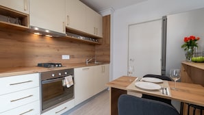 Eine moderne Küche mit Holzschränken, einem Einbauofen und einem Essbereich mit Tisch für zwei Personen.