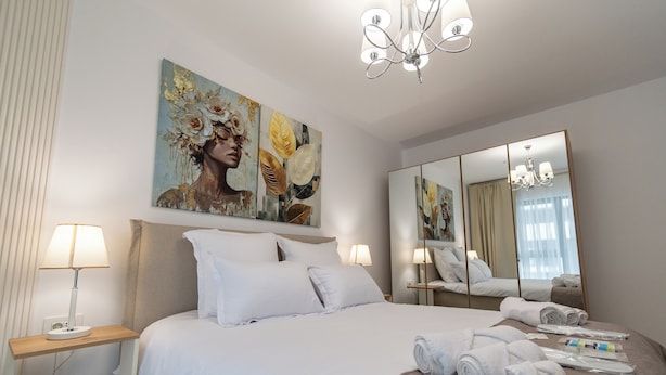 Ein Hotelzimmer mit einem Bett, zwei Nachttischlampen, einem großen Spiegel und einer Chandelüstere.