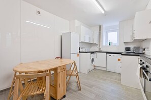 Eine moderne Küche mit weißen Schränken, einem Holztisch und einer integrierten Waschmaschine.