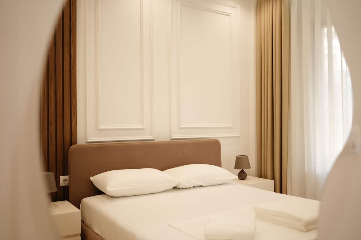 A hotel room with a bed, nightstands, a lamp, and curtains.