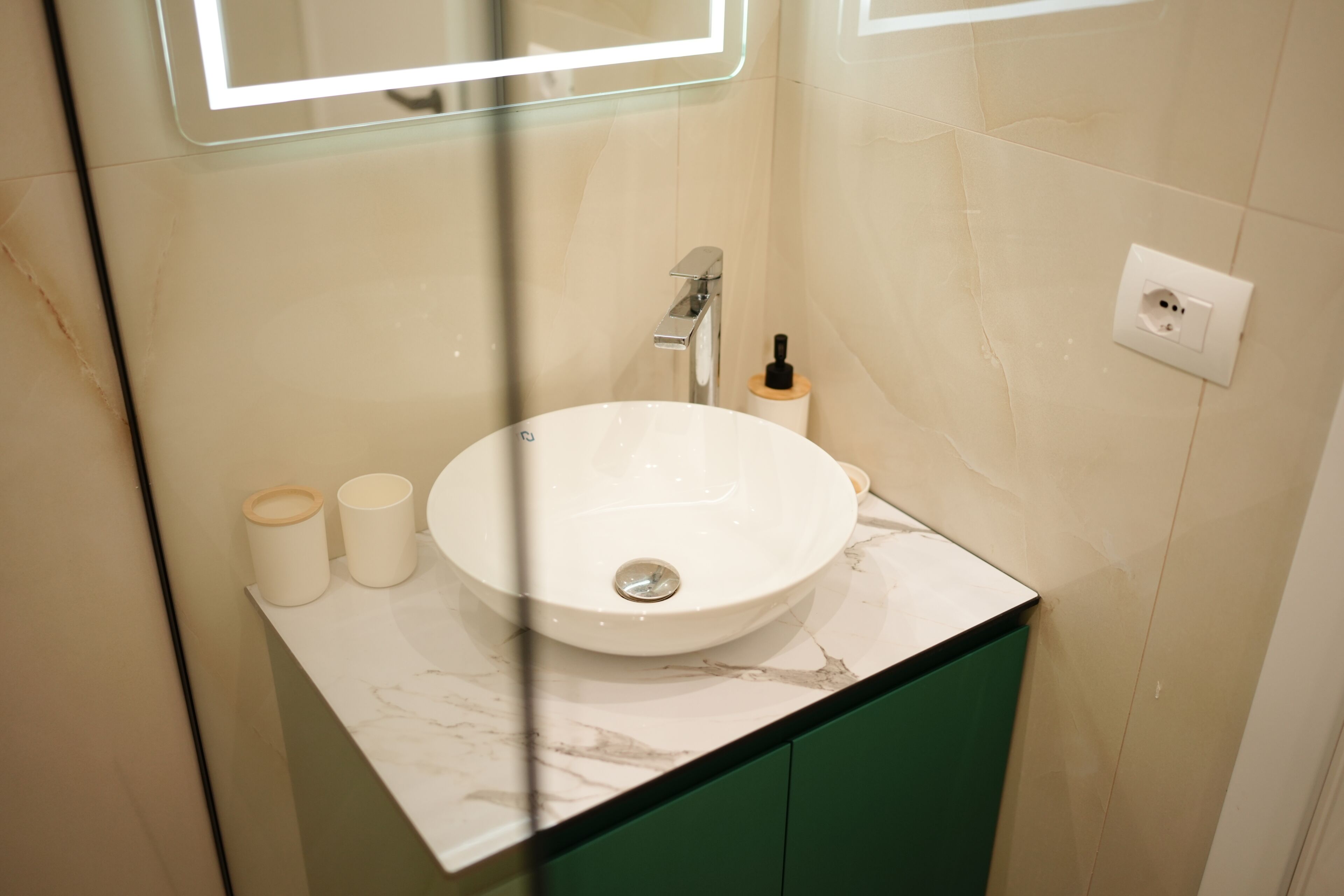 A bathroom with a white sink, green cabinet, and a mirror above the sink.