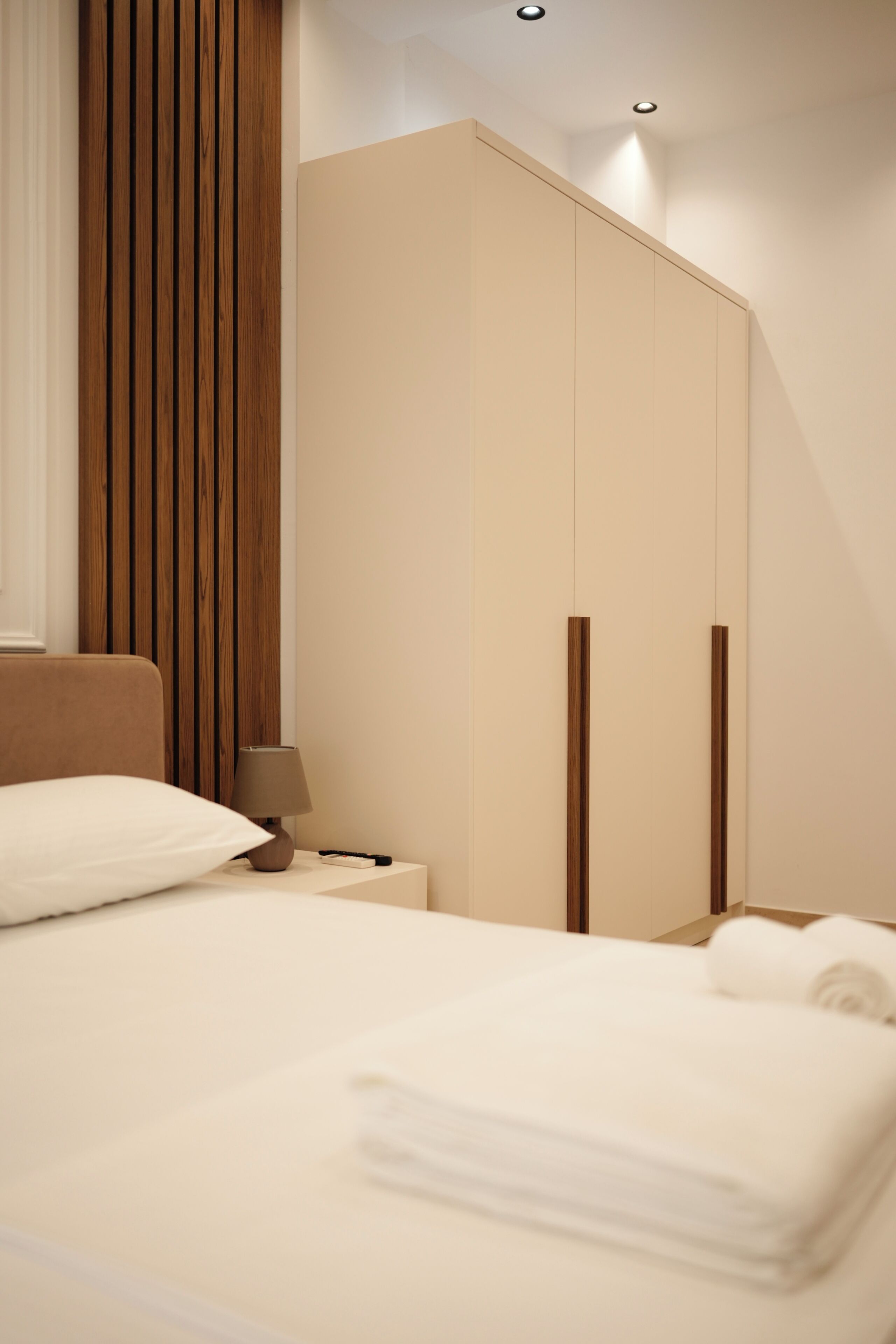 A bedroom with a bed, a nightstand, a lamp, and a wardrobe.