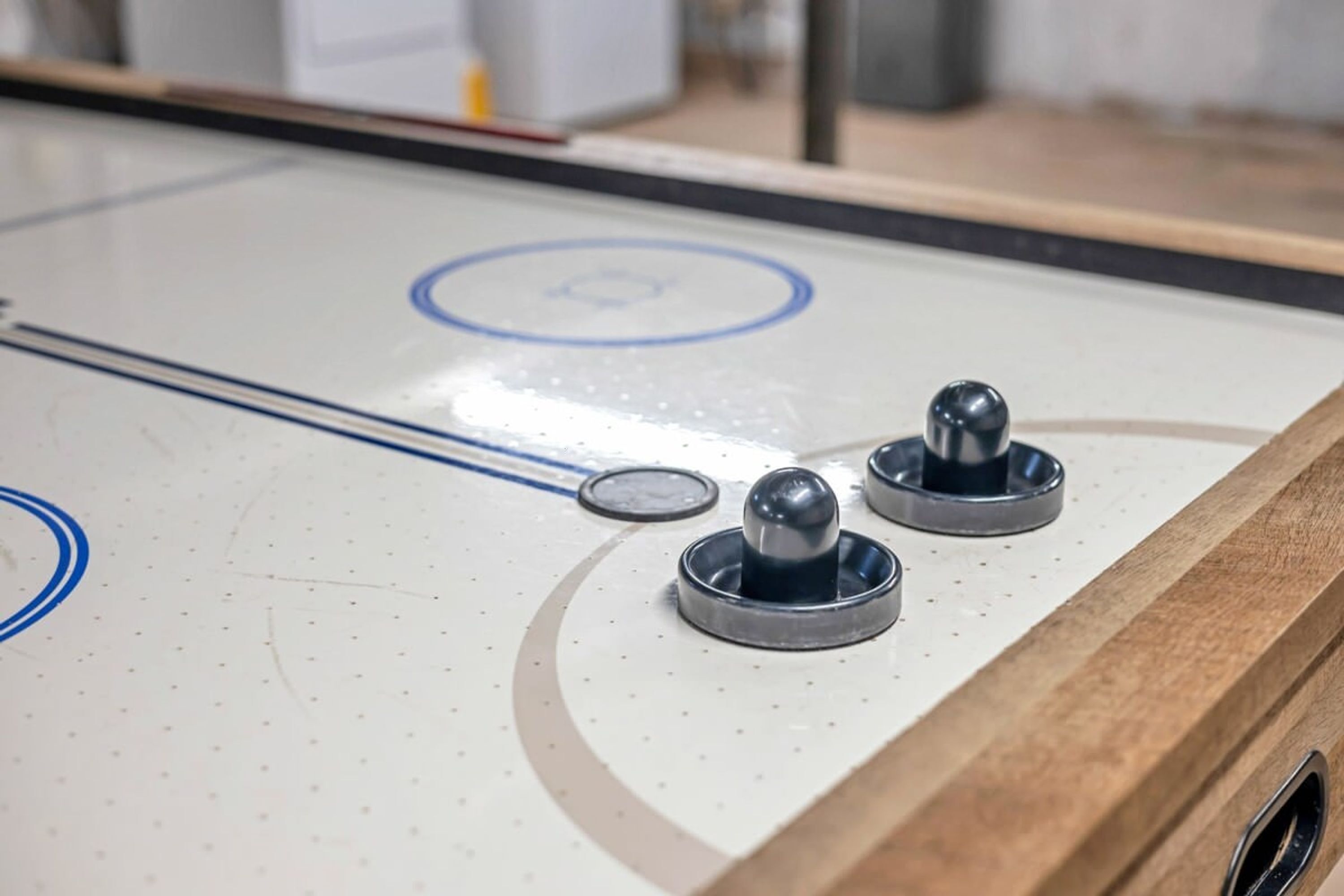A close-up of a shuffleboard table with metal pucks and a circular target.