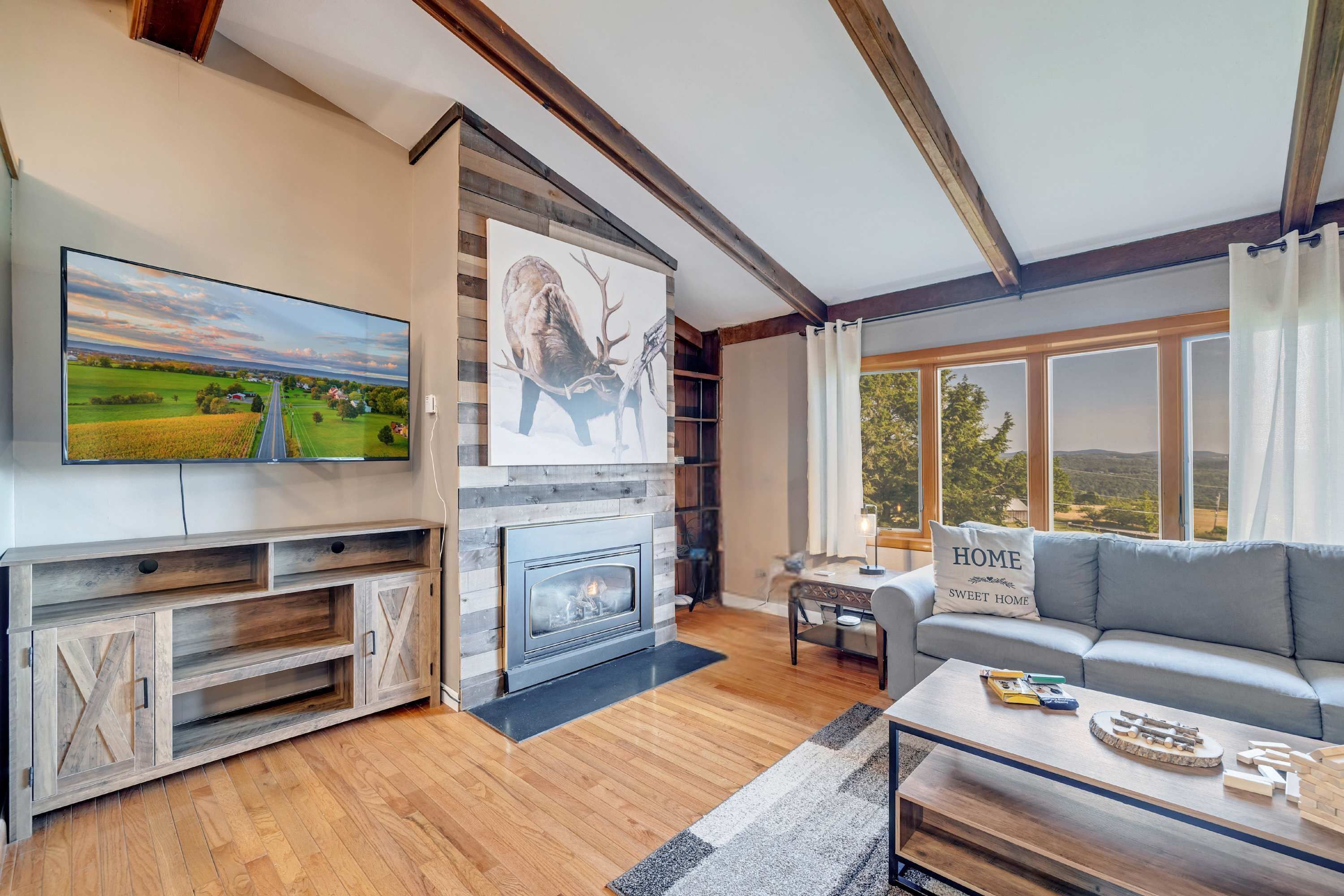 A living room with a fireplace, a television, a sofa, and a large window.