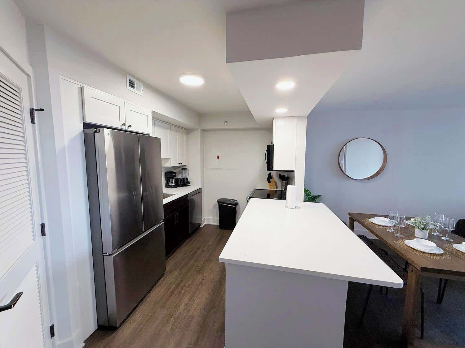 A modern kitchen with a central island, built-in appliances, and a dining area with a table set for two.