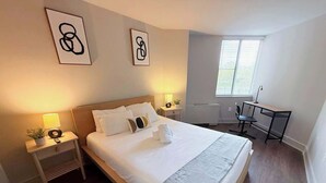 Et hotelværelse med seng, sengeborde, et skrivebord og et vindue.