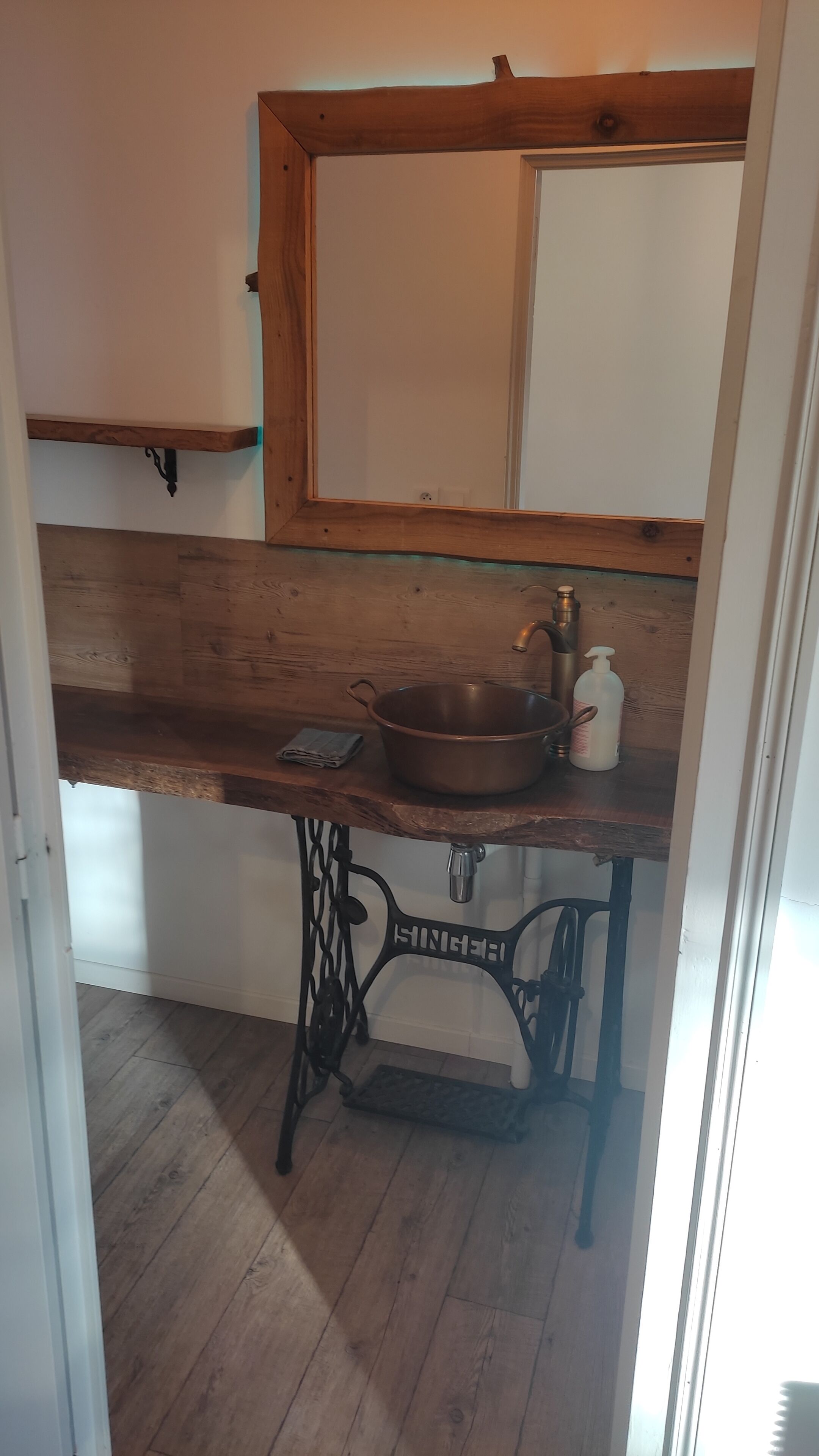 A small kitchen with a wooden countertop, a sink, and a mirror above it.