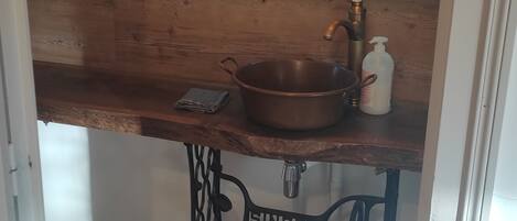 A small kitchen with a wooden countertop, a sink, and a mirror above it.