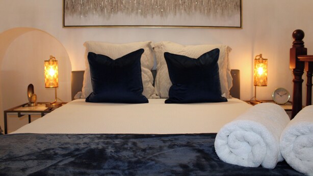 A neatly made bed with two pillows, a bedside table with a lamp, and a wall-mounted artwork. - Loft Studio in San Sebastián St. next to Old San Juan Nightlife (San Juan)