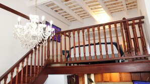 A wooden staircase with a chandelier, a ceiling with exposed beams, and a painting on the wall. - Loft Studio in San Sebastián St. next to Old San Juan Nightlife (San Juan)