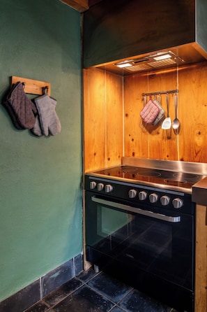 A kitchen with a stove, oven, and hanging utensils.