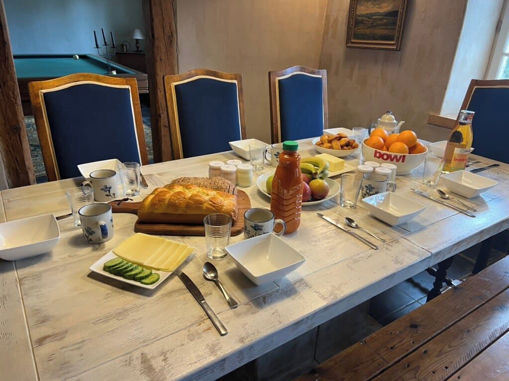 A dining table set with various dishes, including bread, fruit, and condiments.