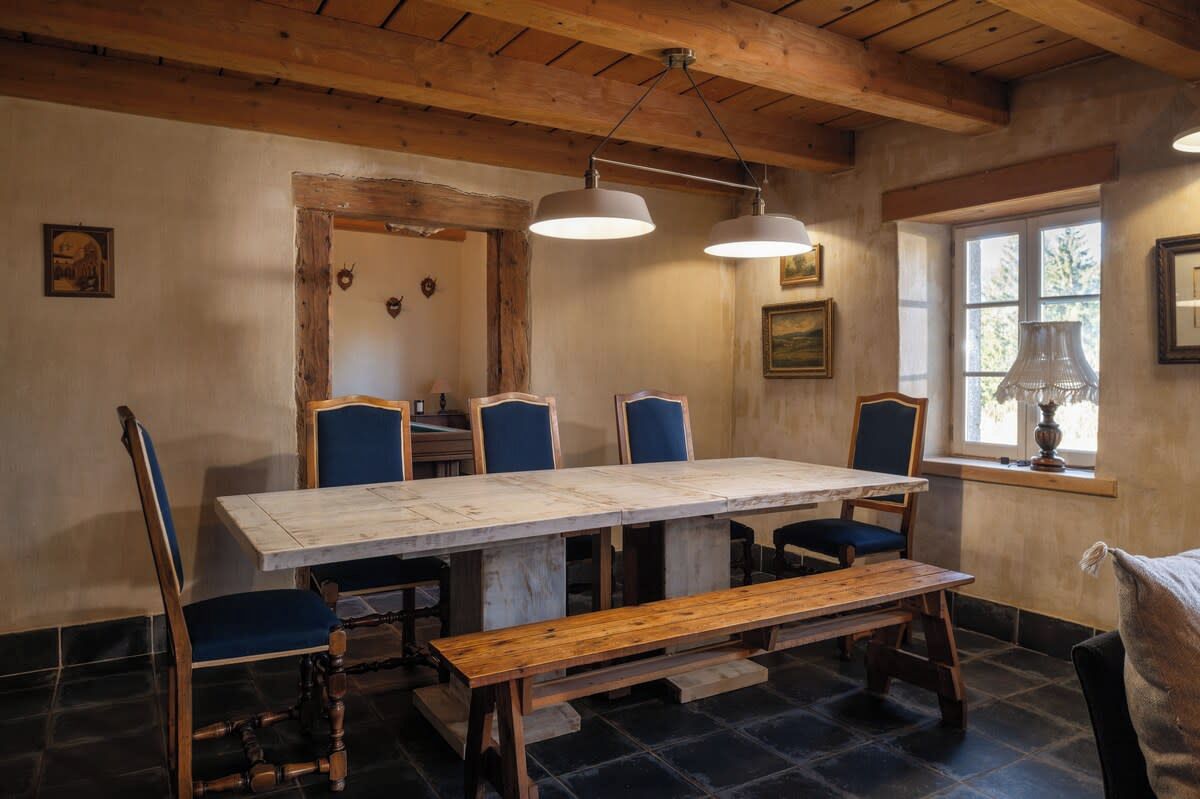 Un'accogliente sala da pranzo con un lungo tavolo in legno, sedie rivestite di blu e una panca.
