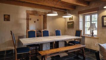 Un'accogliente sala da pranzo con un lungo tavolo in legno, sedie rivestite di blu e una panca.