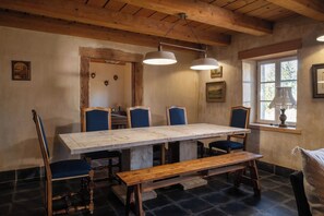 A rustic dining area with a long wooden table, blue upholstered chairs, and a bench.