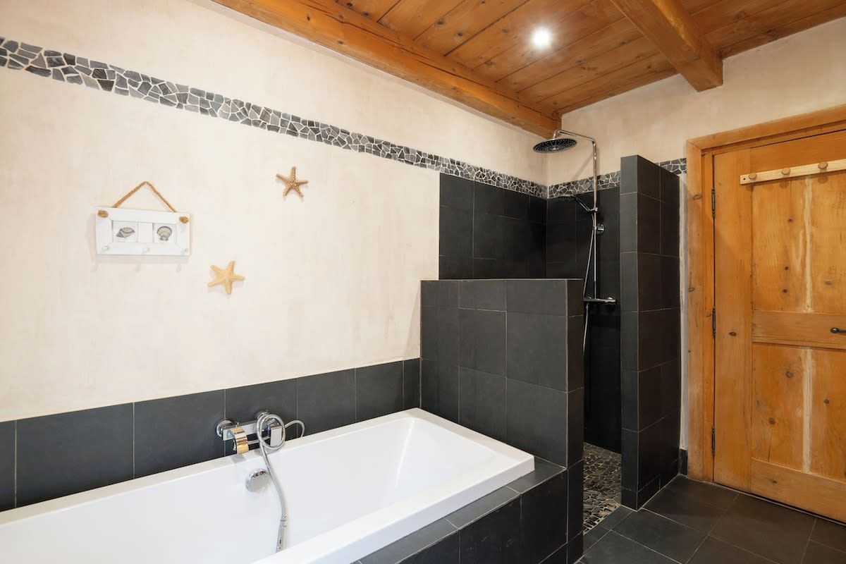 Une salle de bain avec une baignoire, une douche et une porte en bois.