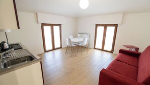 A compact living space with a kitchenette, a dining area, and a red sofa.