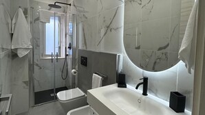 A modern bathroom with a large mirror, a shower, a sink, and a toilet. - STILL HOUSE 1904 (San Nicola Arcella)