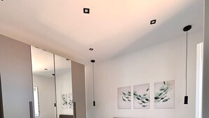 A modern bedroom with a large bed, a mirror, and artwork on the wall. - STILL HOUSE 1904 (San Nicola Arcella)