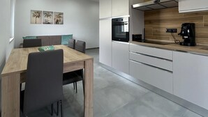 A modern kitchen with white cabinets, a wooden countertop, and a built-in oven. - STILL HOUSE 1904 (San Nicola Arcella)