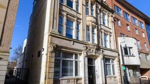 Un immeuble à étages doté d’un style architectural classique, caractérisé par de grandes fenêtres et une entrée imposante.