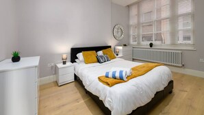 Une chambre à coucher avec un lit, des tables de chevet, un radiateur et une fenêtre avec des stores.