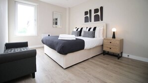 Una camera da letto moderna con un grande letto, un comodino, una sedia e opere d'arte alle pareti.