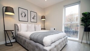 Una camera da letto con un letto grande, due lampade sui comodini, una finestra e un'opera d'arte al muro.