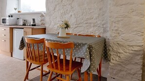 A dining area with a table covered in a polka dot tablecloth, surrounded by wooden chairs, a white vase with flowers, and a kitchen in the background. - 1 Bed Home • Parking • Great for Contractors (Gorseinon)